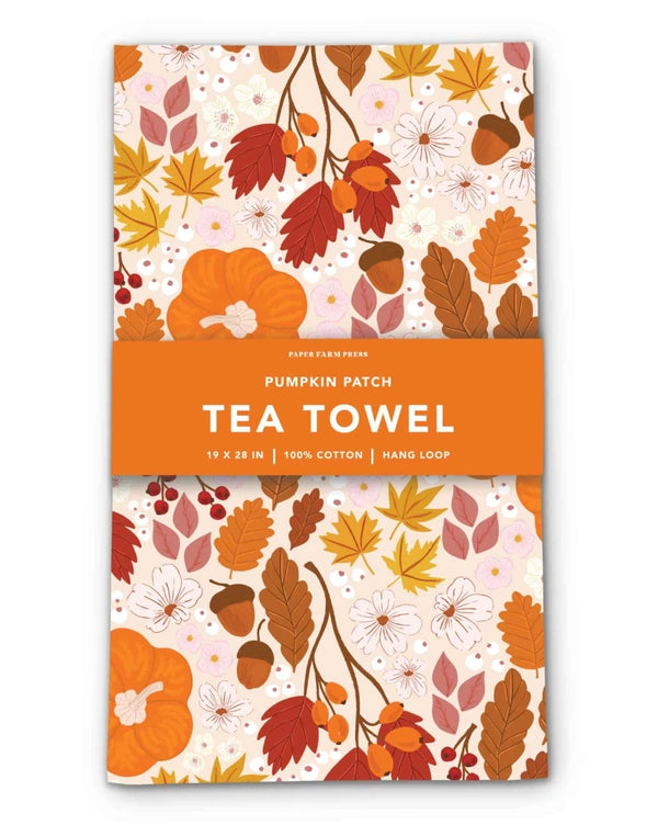 Tea towel with autumnal design featuring leaves and pumpkins on a white background