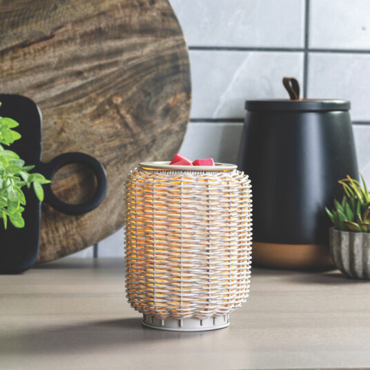 Wicker lantern with a candle on a table with decorative items in the background