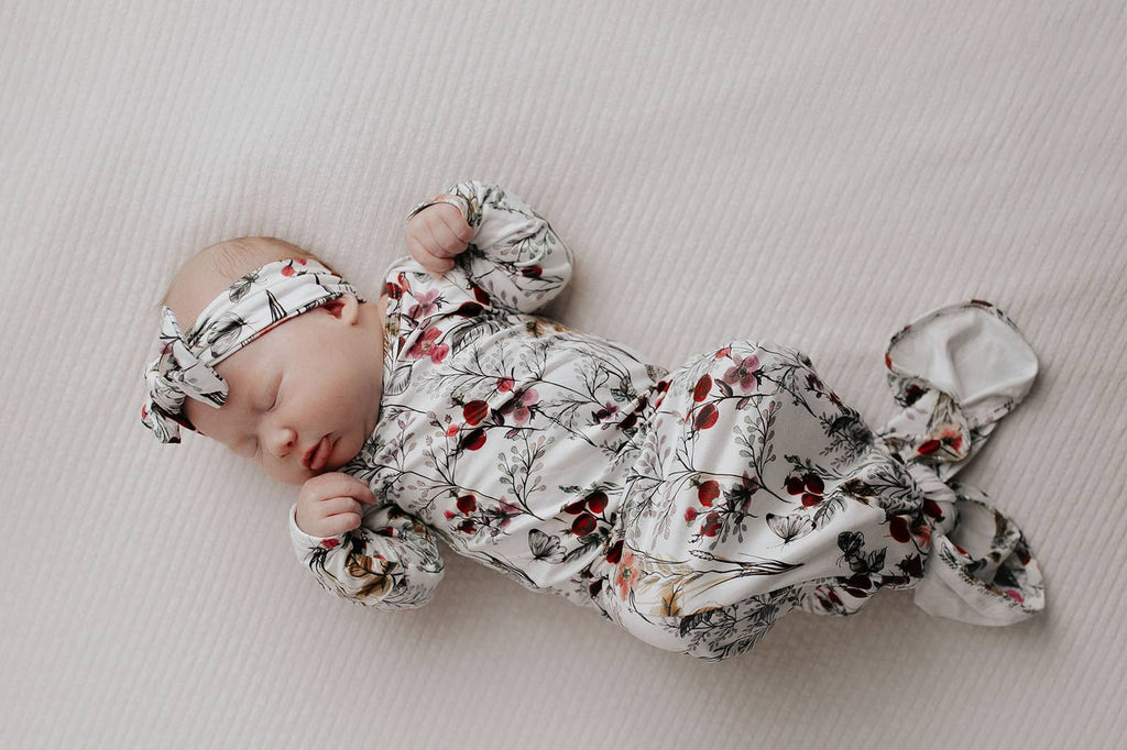 floral gown on a baby laying on a white background