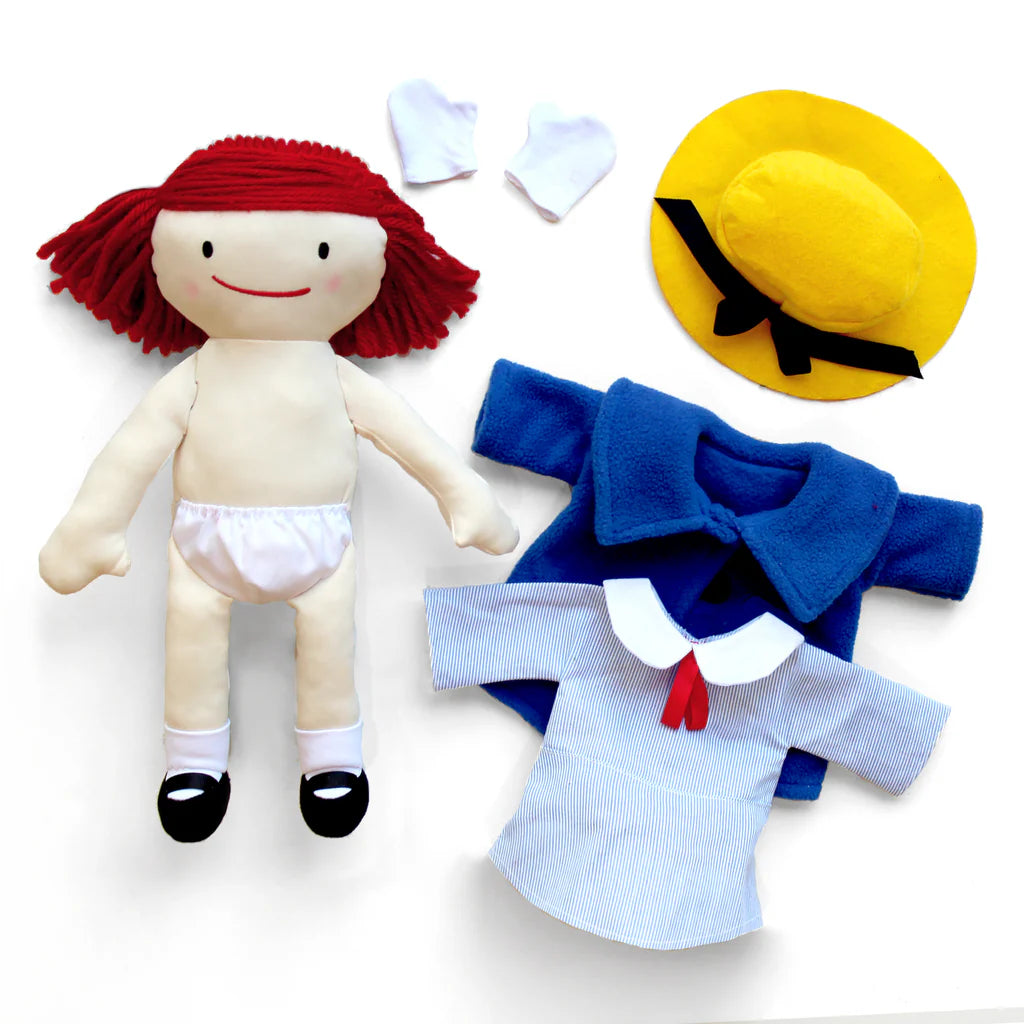Toy doll with red hair and a yellow hat, along with clothing items on a white background