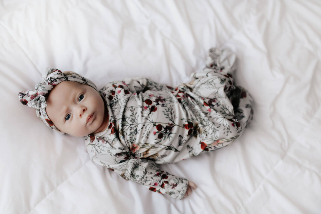 floral gown on a baby laying on a white background