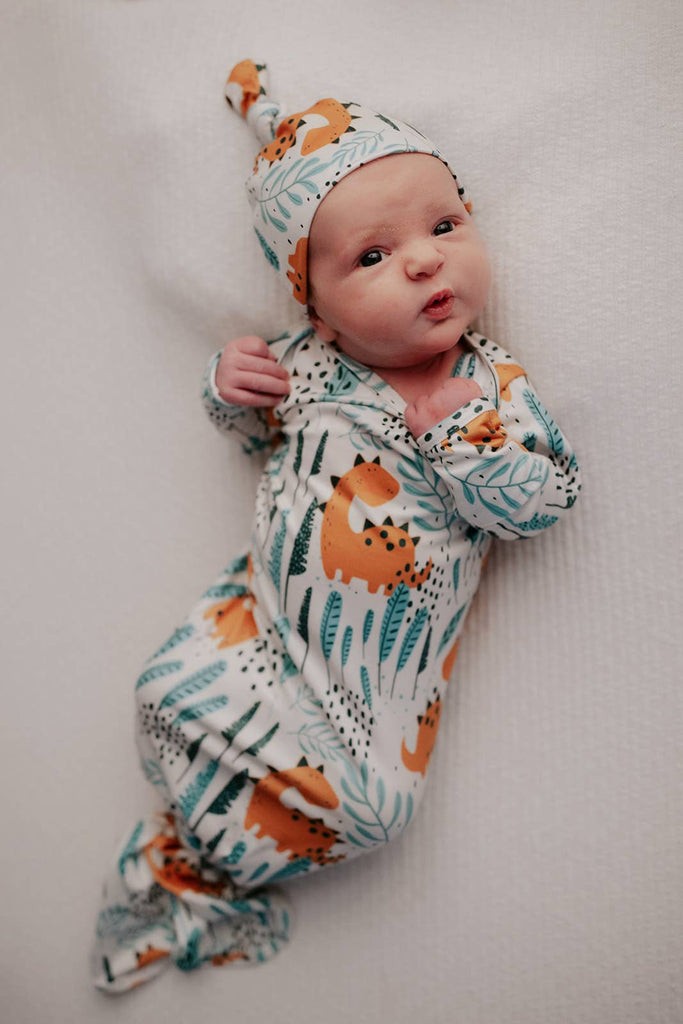 dino gown on a baby in a wood bassinet 