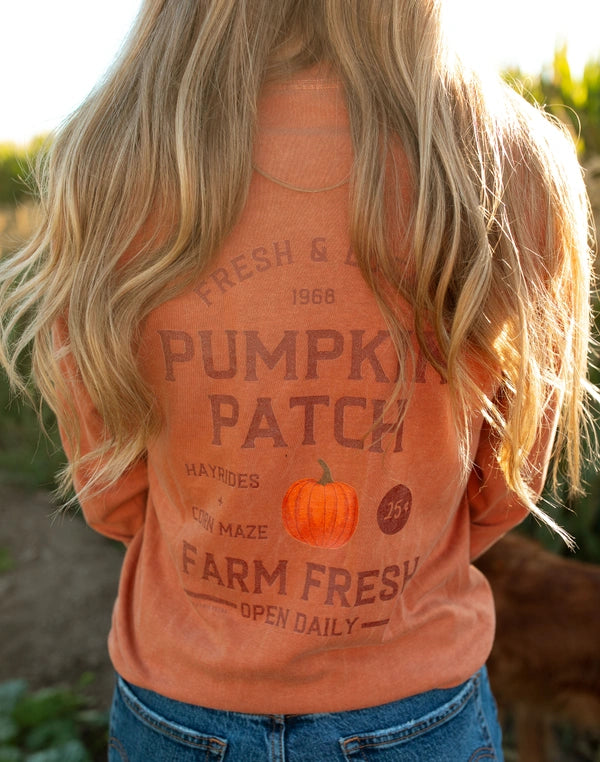 Person wearing an orange 'Pumpkin Patch' shirt in a field