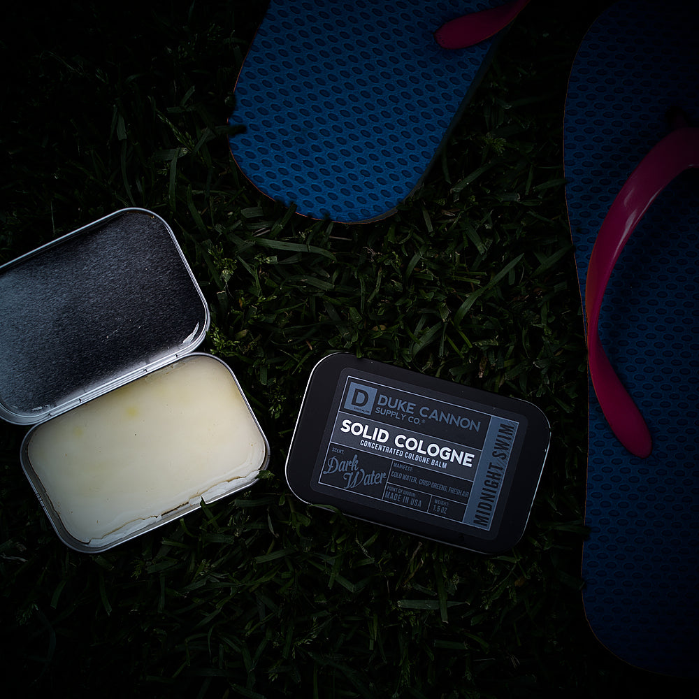 duke cannon solid cologne on a grass background
