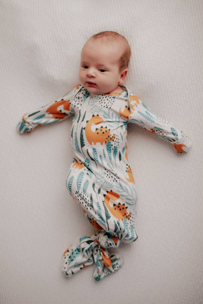 dino gown on a baby in a wood bassinet 