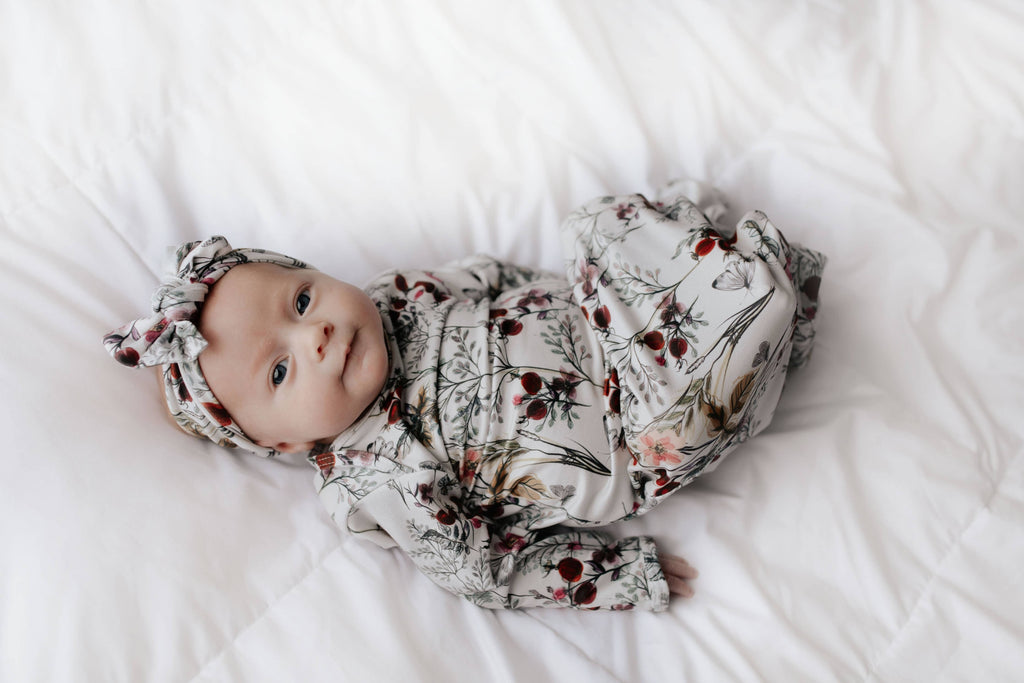 floral gown on a baby laying on a white background