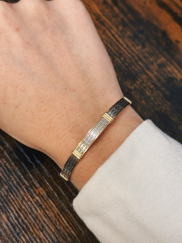 handmade straight wire bracelet being worn on a wooden table