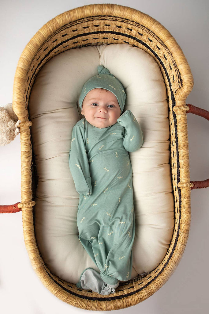 baby laying in bassinet wearing gown 