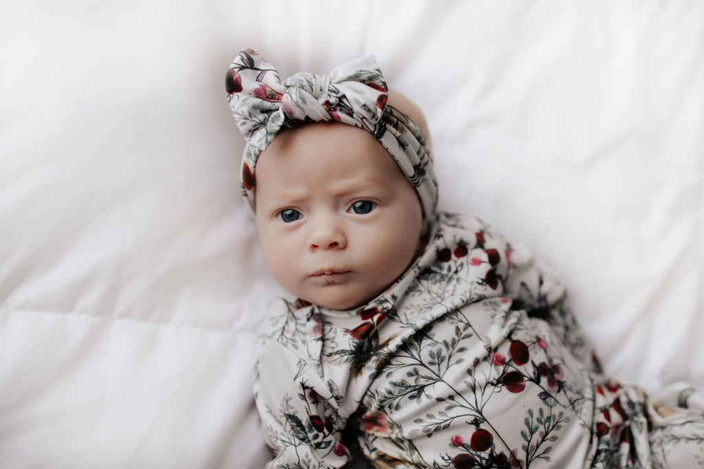 floral gown on a baby laying on a white background