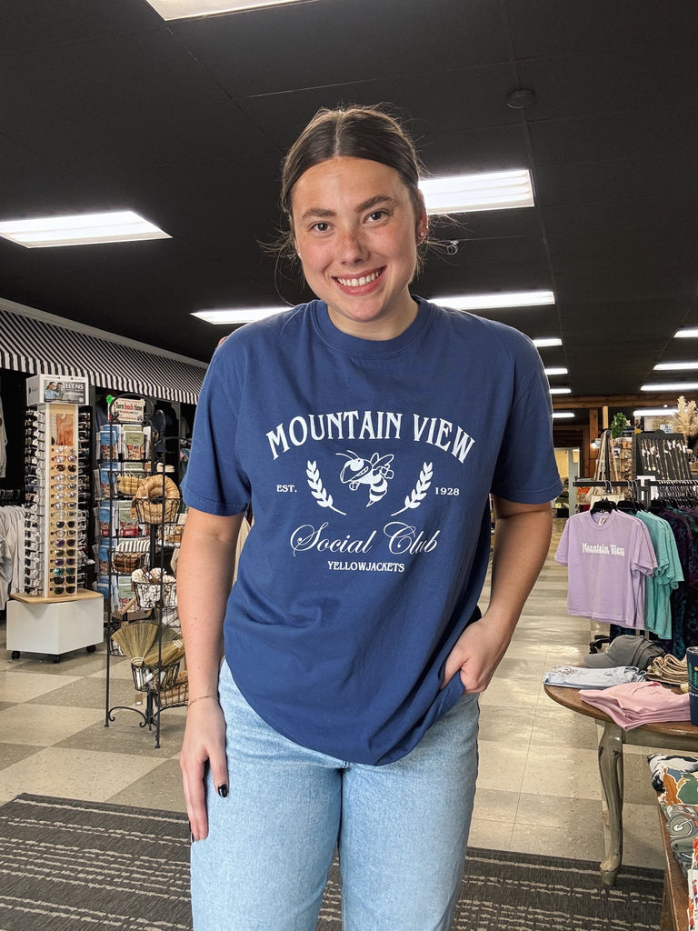 Person wearing a blue 'Mountain View Social Club' t-shirt in a store setting