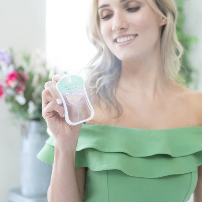 Woman in a green dress holding a small green and white product.