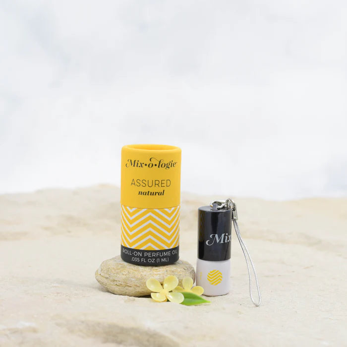 Mix-o-logic assured natural roll-on perfume with packaging on a textured surface.