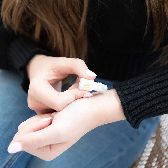 Person applying a small tube of cream to their wrist