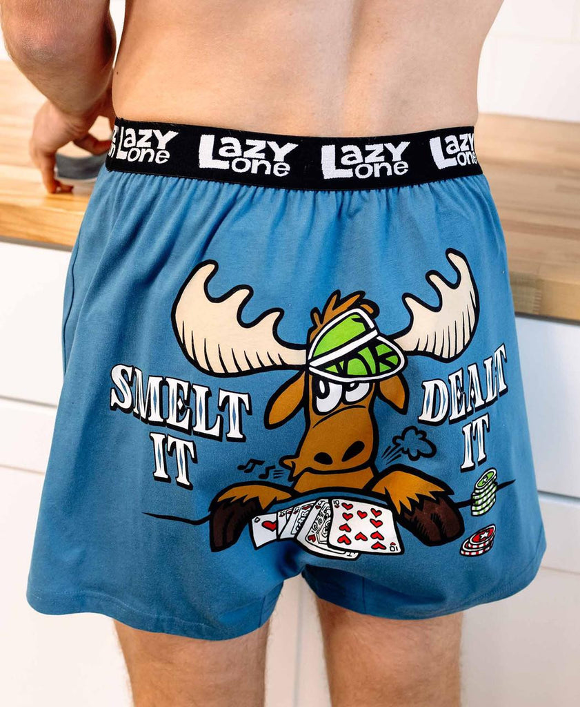 Blue boxer briefs with a cartoon moose design and text on a wooden surface.