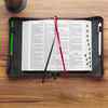 Open book with bookmarks and pens on a wooden surface