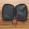 Open travel case with black and red straps on a wooden surface