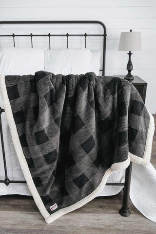 gray plaid blanket on the end of a bed with white comforter