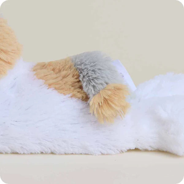 Plush toy resembling a dog with white, brown, and gray fur on a beige background