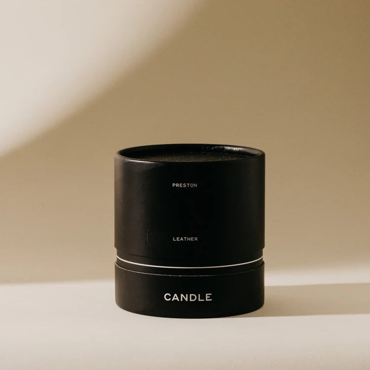 Black candle container with 'Preston' branding on a beige background