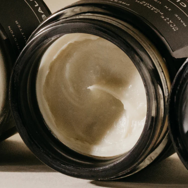 Open jar of cream with visible brand name on a neutral background