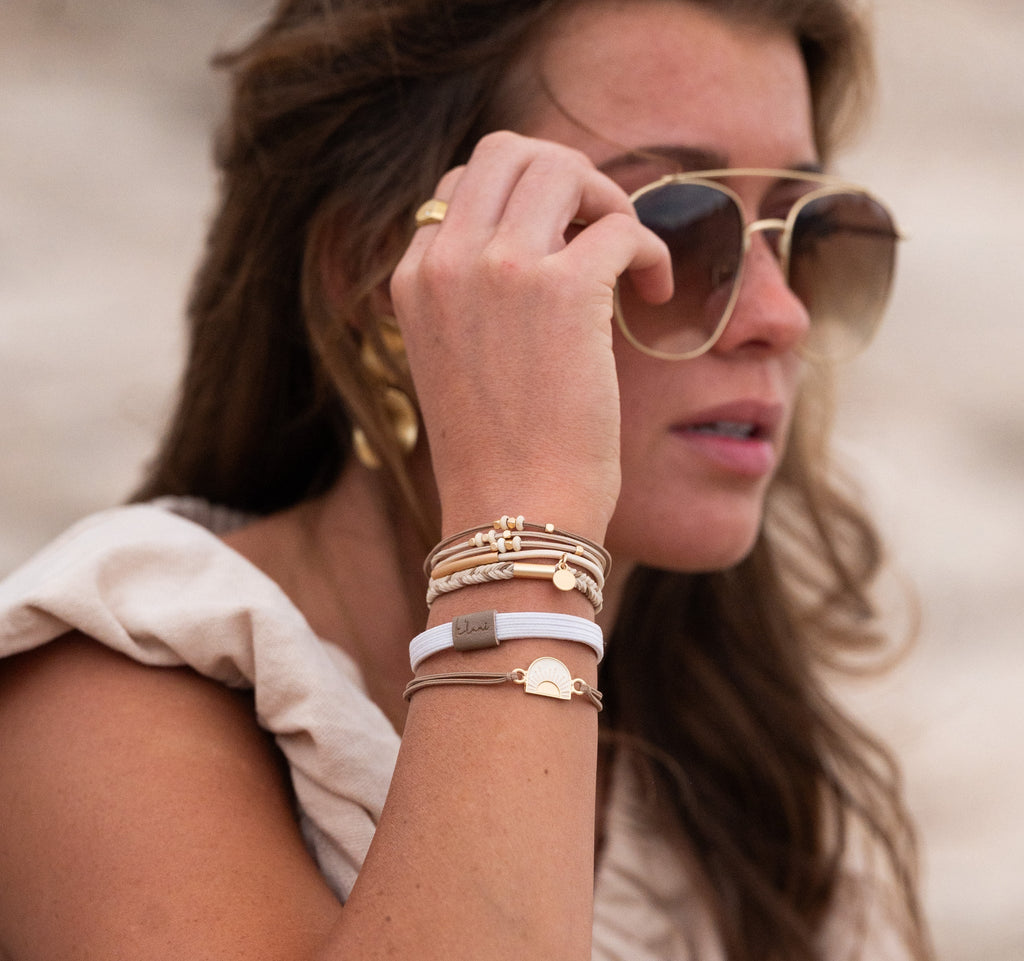 Woman wearing sunglasses and multiple bracelets on a blurred background