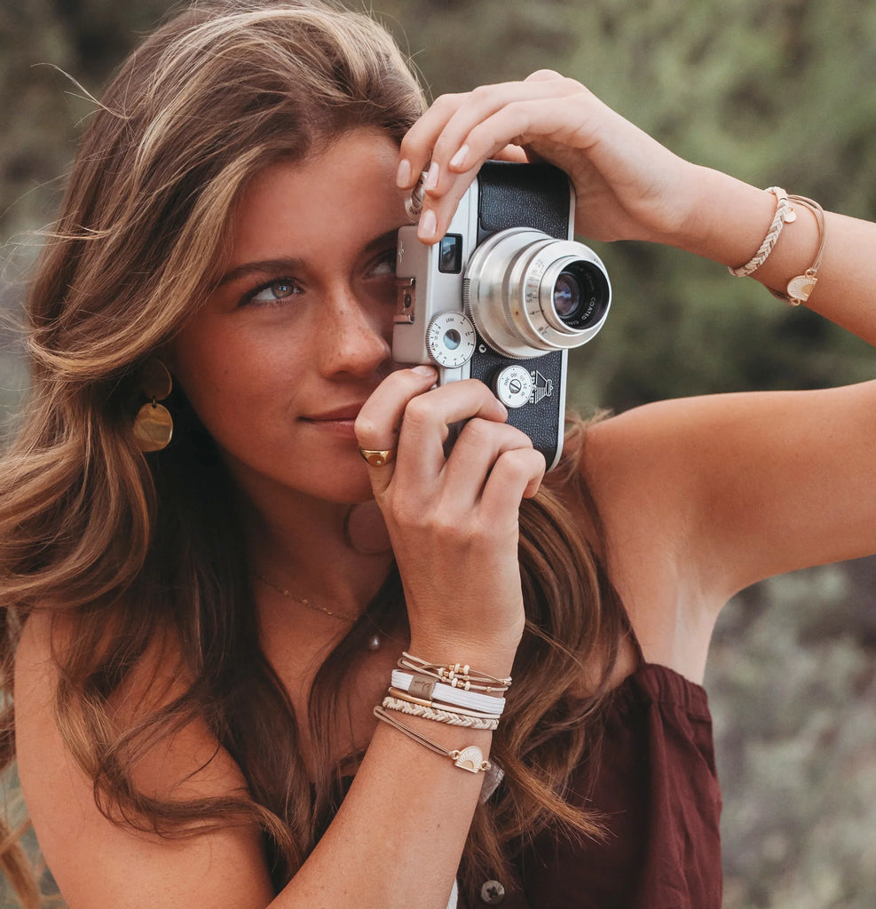 Woman holding a vintage camera with a blurred natural background