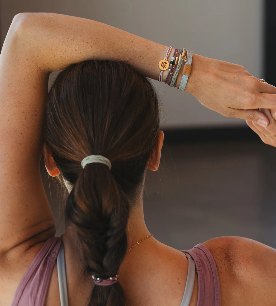 Person with braided hair and multiple bracelets on a blurred background