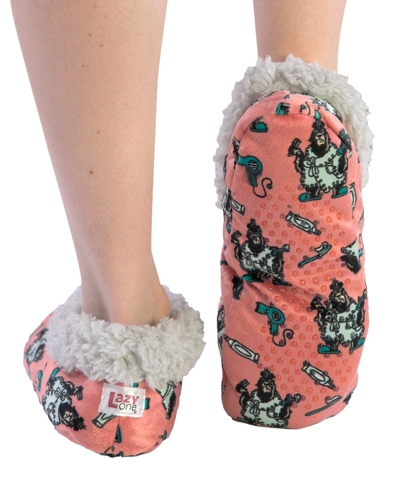 Pink slipper socks with dog pattern and fluffy interior worn by a person on a white background