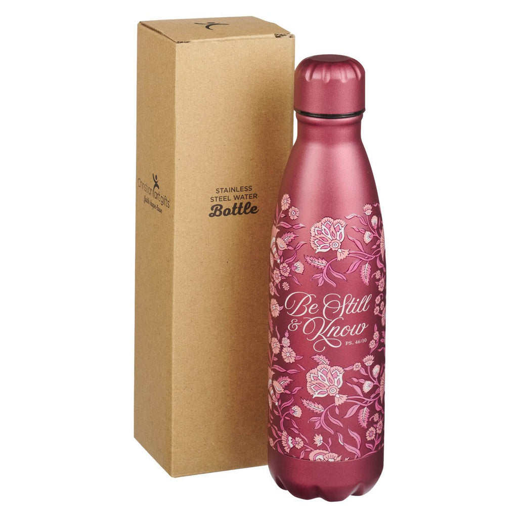 Pink floral-patterned water bottle with 'Be Still & Know' text next to a cardboard box on a white background
