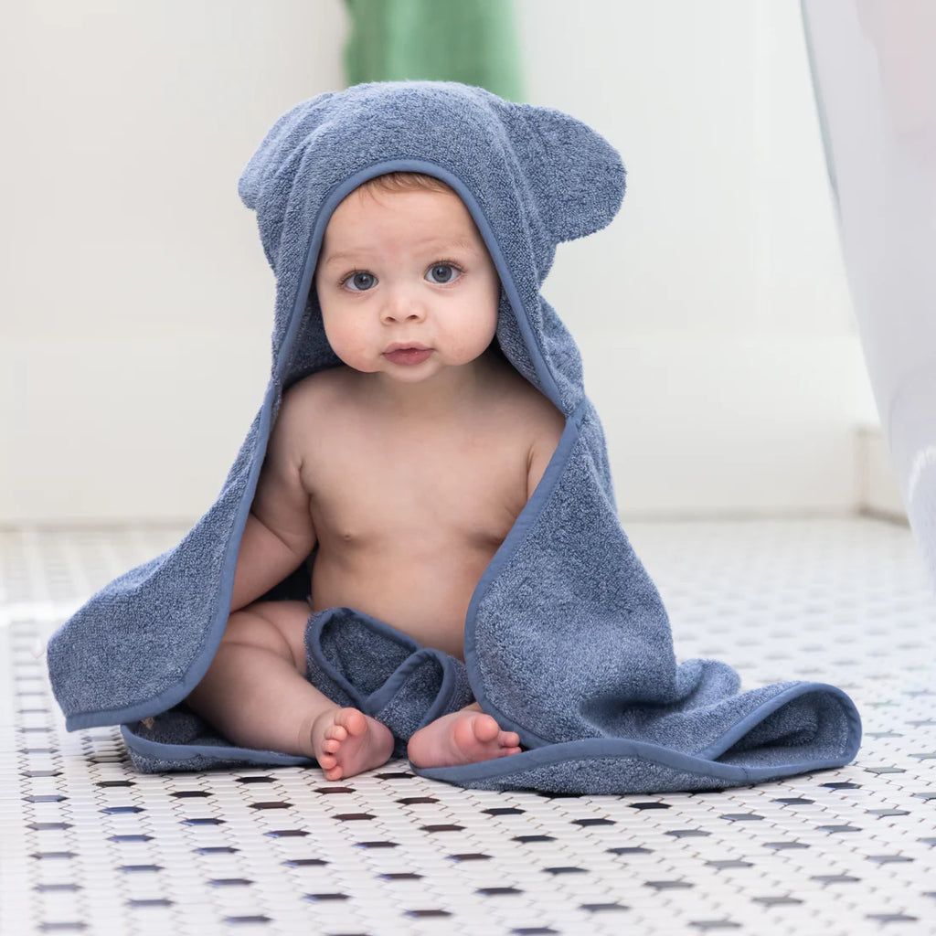 Baby wrapped in a blue hooded towel on a patterned surface