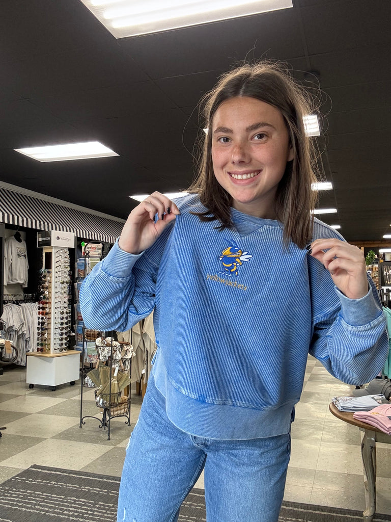 Person wearing a blue sweater with an emblem in an indoor setting