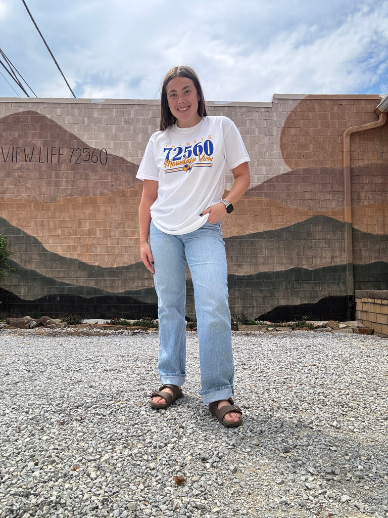 Person standing on a driveway with a house in the background