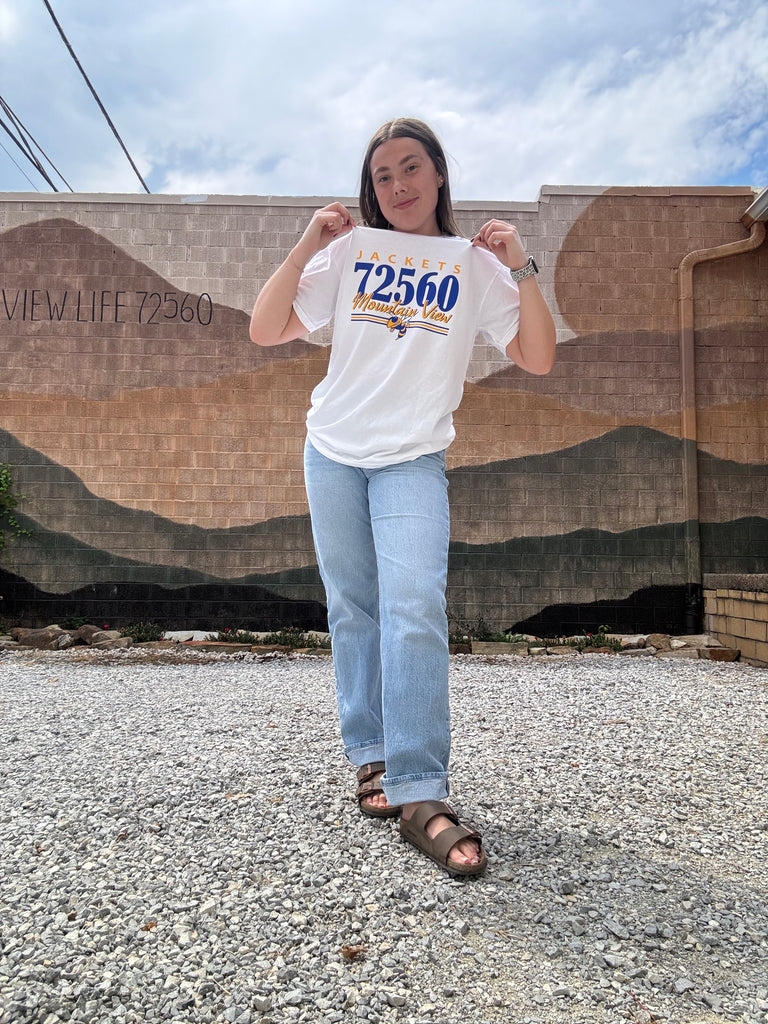 Person wearing a white t-shirt with text standing on a road.