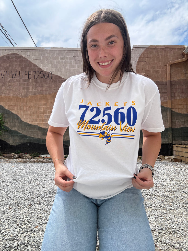 Person wearing a white t-shirt with text, standing outdoors.