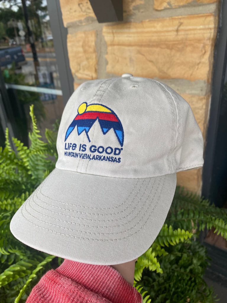 life is good hat being worn in front of rock building
