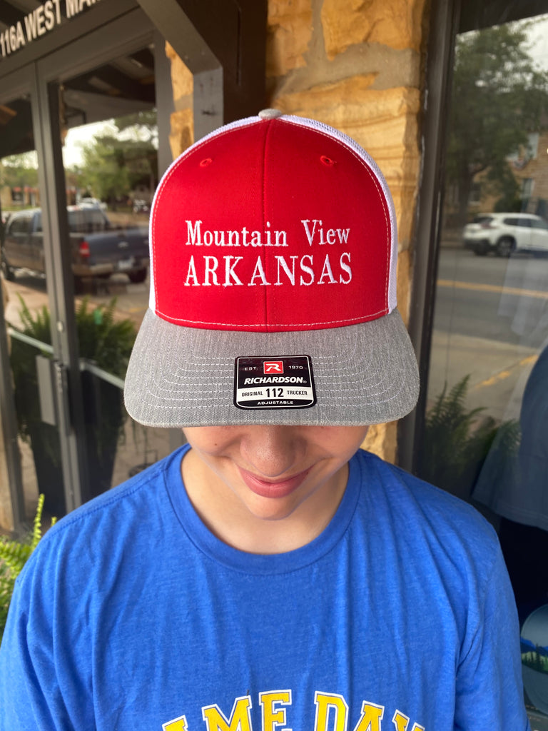 mountain view arkansas hat being worn in front of a rock building