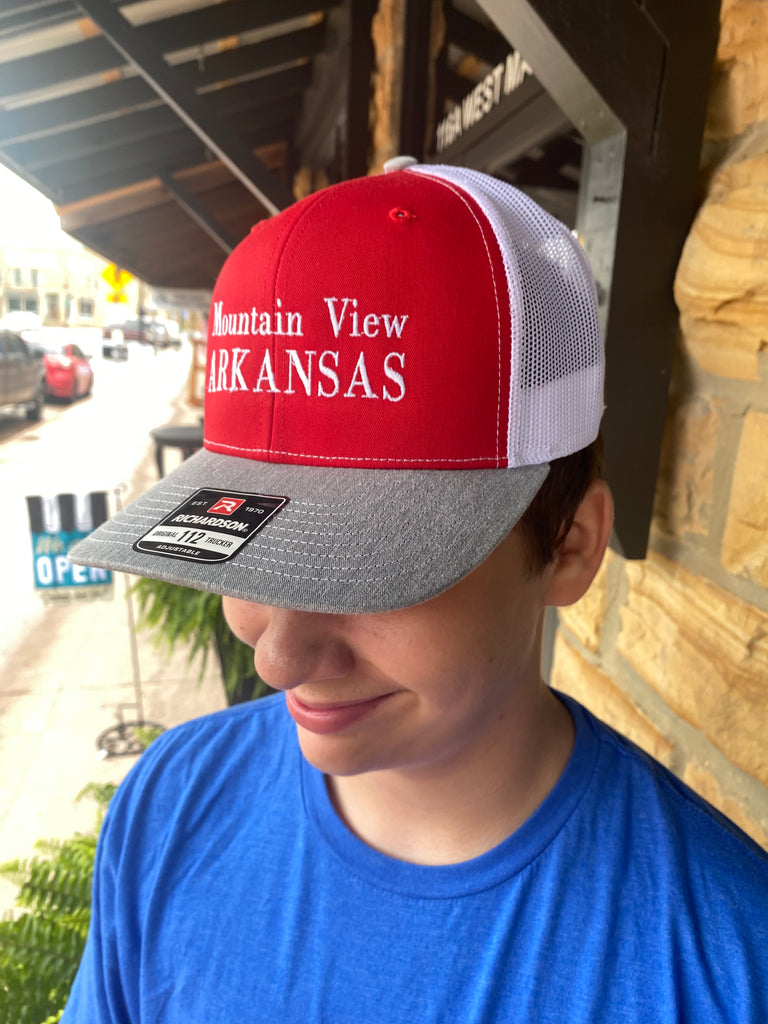 mountain view arkansas hat being worn in front of a rock building
