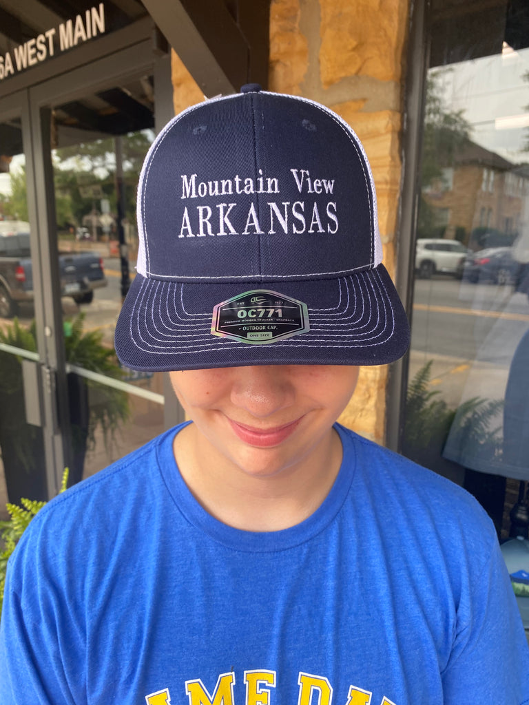 mountain view arkansas hat being worn in front of a rock building