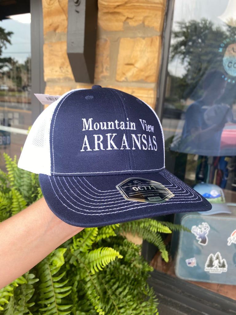 mountain view arkansas hat being worn in front of a rock building