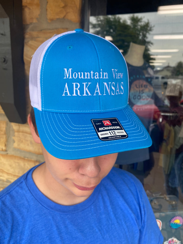 mountain view arkansas hat being worn in front of a rock building