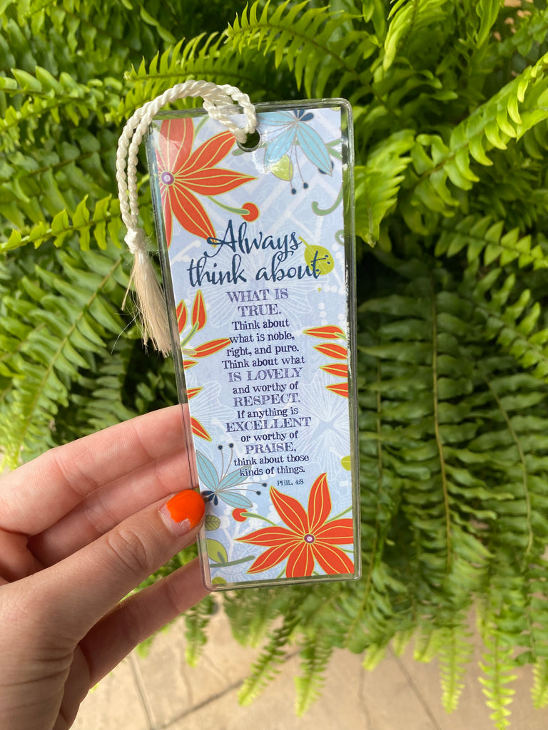 always think about bookmark in a clear plastic cover being held in front of a green fern