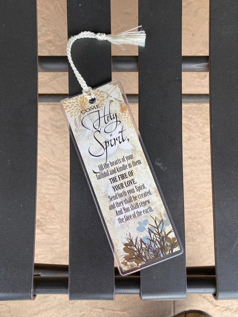 come Holy Spirit clear plastic enclosed bookmark laying on a metal bench