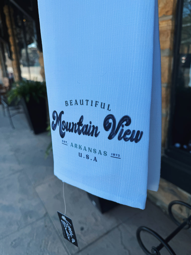 beautiful mountain view tea towel in front of a black metal bench close up