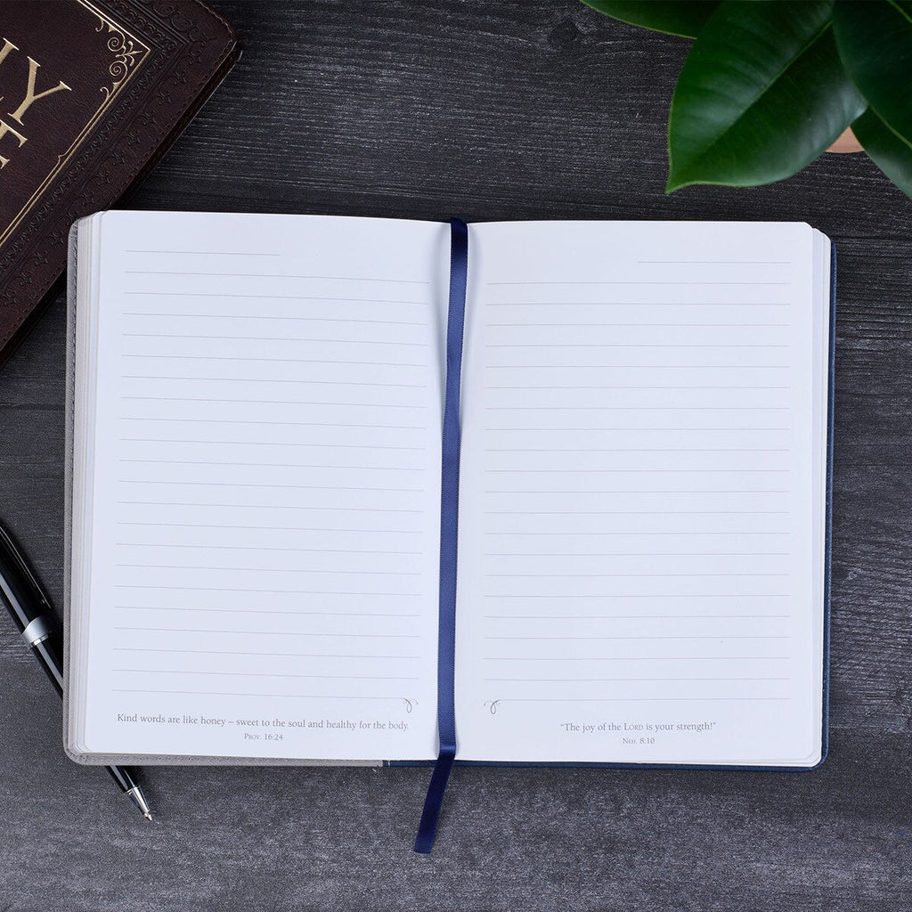 Open notebook on a dark surface with a plant in the corner