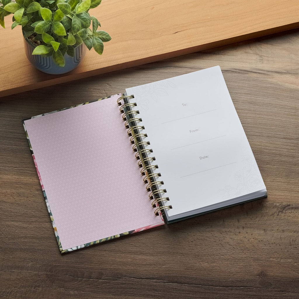 Open notebook on a wooden surface with a plant in the background