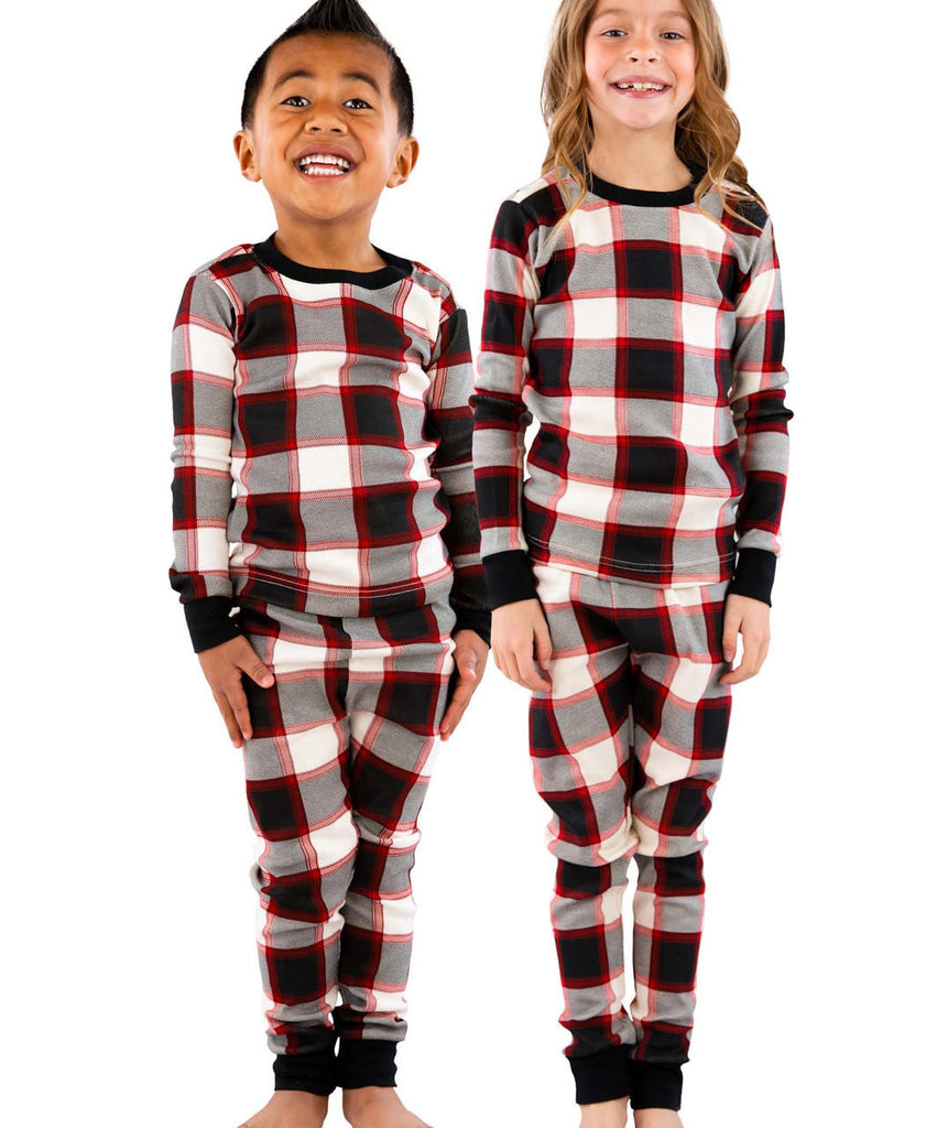 Two children wearing red and black plaid pajamas on a white background