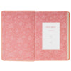 Pink floral-patterned Bible with a white label on a white background