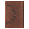 Brown leather notebook with embossed thorn branch design on a white background