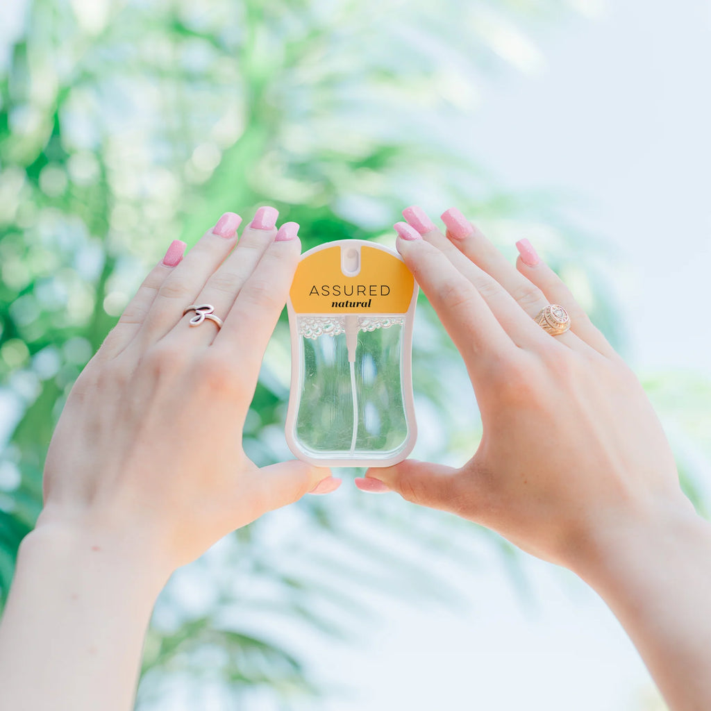 Hands holding a transparent container with 'Assured' branding against a blurred green background