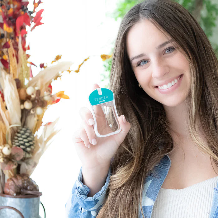 Woman holding a clear plastic item with a blue label in front of a decorative background